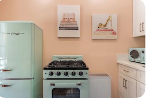 A retro kitchen with a vintage refrigerator, a stove, and a microwave.