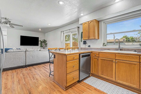 A kitchen with wooden cabinets, a dishwasher, a window, and a ceiling fan.