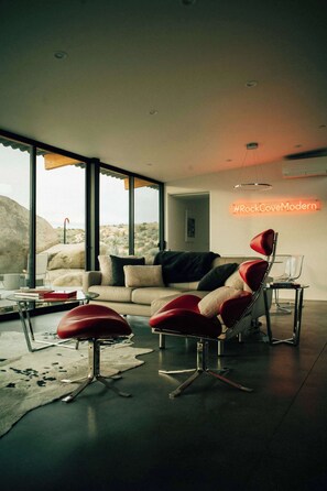 Un salon moderne avec un canapé, des fauteuils rouges et une table basse en verre.