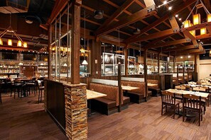 Ein Restaurant mit Holzbalken, Steinverkleidungen und einer Bar.