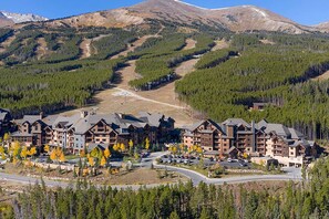 Eine Lodge mit mehreren Gebäuden, ein Ski-Hang im Hintergrund und eine Straße, die zum Eingang führt.