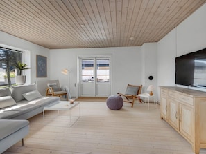 Ein modernes Wohnzimmer mit einer Couch, einem Couchtisch und einem Fernseher.