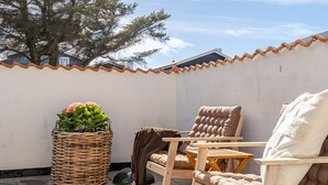 A patio with a wicker basket, two wooden chairs, and a cushion. - "Senija" - 175m from the sea by Interhome (Blokhus)