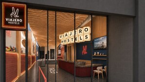 A modern hotel entrance with a visible reception desk, a staircase leading to the upper floor, and a sign indicating the hotel's name. - Viajero Lima - Miraflores Hostel (Lima)