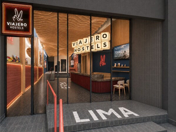 A modern hotel entrance with a visible reception desk, a staircase leading to the upper floor, and a sign indicating the hotel's name. - Viajero Lima - Miraflores Hostel (Lima)