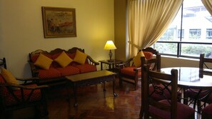 Una habitación con sofá, sillas, una mesa, una lámpara y un cuadro en la pared.