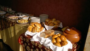 A buffet table with various food items and stacked plates.