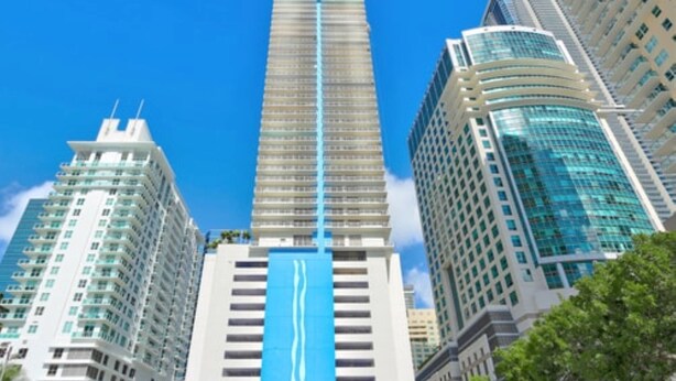 Ein Hochhaus mit auffälligem, blauen vertikalen Streifen, umgeben von weiteren hohen Gebäuden.