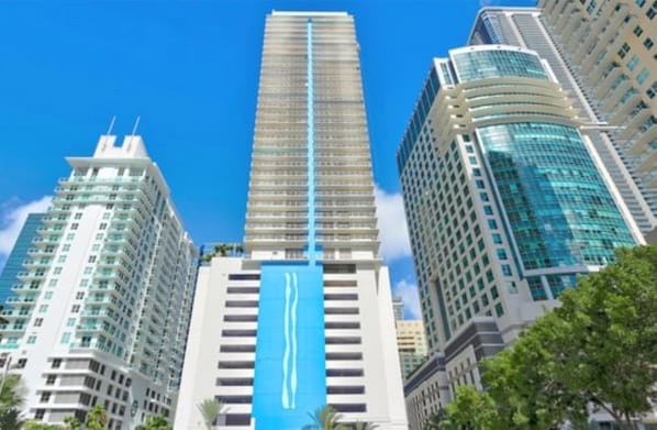 A high-rise building with a prominent blue vertical stripe, surrounded by other tall buildings. - The Brickell Estates (Miami)