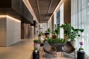 A modern hallway with a wooden ceiling, potted plants, and two chairs. - The Brickell Estates (Miami)