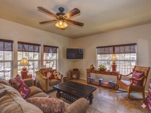 A living room with a ceiling fan, a TV, a coffee table, a sofa, a chair, and a bookshelf. - Union Street Townhouse 2BD/1.5BA Near Whiskey Row (Prescott)