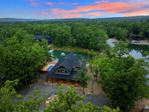 Un chalet doté d’une piscine, entouré d’une forêt dense et bordé d’un lac.