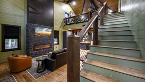 A spacious interior with a fireplace, a staircase, and a seating area.