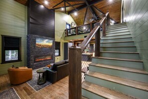 Un intérieur spacieux avec une cheminée, un escalier et un coin salon.
