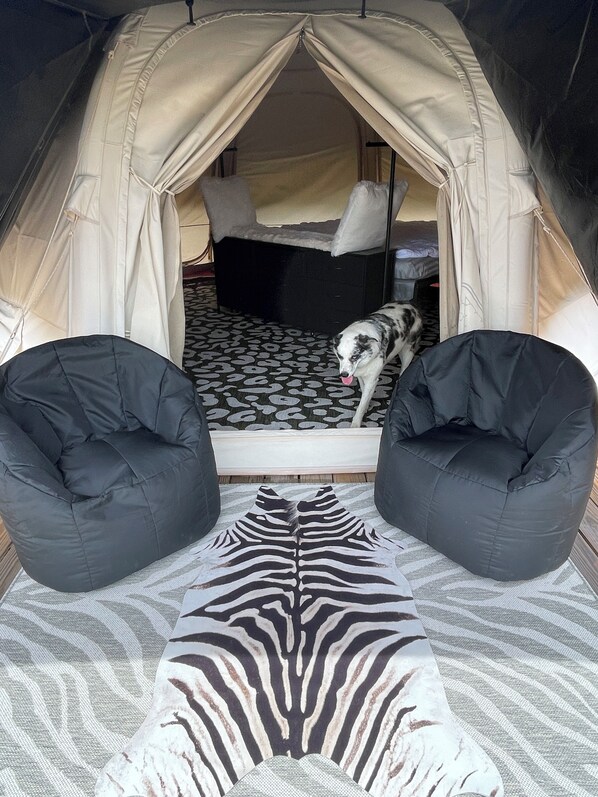A tent with a bed, two black bean bags, and a zebra-patterned rug.