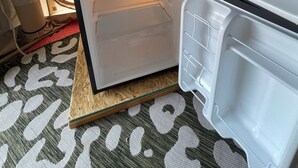 A compact refrigerator with two shelves and a freezer compartment, placed on a wooden floor with a patterned mat. - Air conditioned Glamping Tent overlooking a beautiful orchard (Merritt)