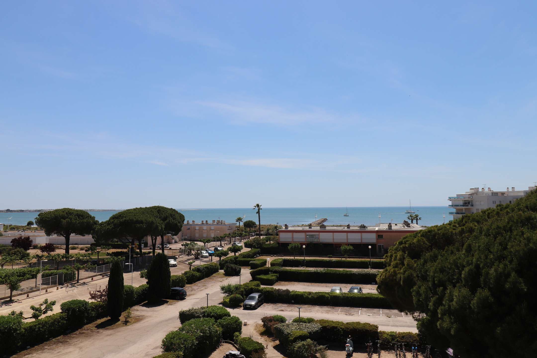 Zona residencial a la costa, amb vista despejada al mar, un aparcament i talls de setges ben arreglats.