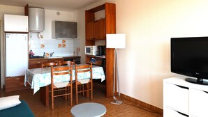 A compact kitchen with a dining area, a flat-screen TV, and a water heater. - 2 rooms sea view Boucanet parking beaches 200m away (LE GRAU DU ROI)