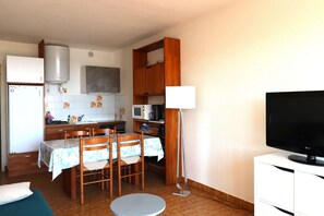 A compact kitchen with a dining area, a flat-screen TV, and a water heater. - 2 rooms sea view Boucanet parking beaches 200m away (LE GRAU DU ROI)