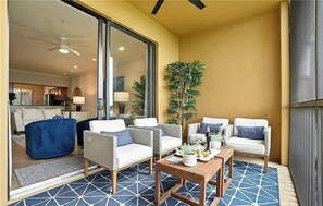 Een balkon met rieten meubilair, een houten tafel en een bloempot.
