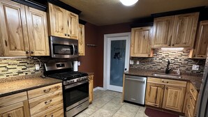 A kitchen with wooden cabinets, a stainless steel refrigerator, a microwave, an oven, and a dishwasher. - The Gathering Place - Large home, 6 bedrooms, 11 beds, beautiful fenced backyard (Vernal)