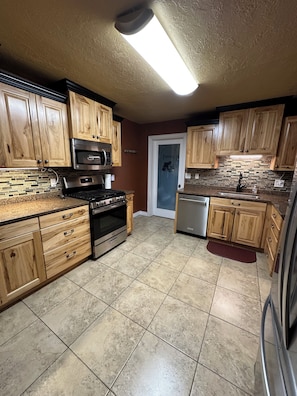 Una cocina con armarios de madera, un refrigerador de acero inoxidable, un microondas, un horno y un lavavajillas.