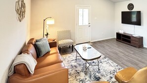 Una sala de estar con sofá, mesa de centro y mueble para televisión.