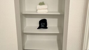 Un couloir étroit aux murs blancs et au plancher en bois.
