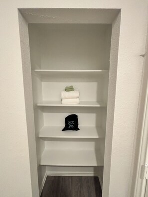 Kapea käytävä, jonka seinät ovat valkoiset ja lattia puuta.