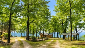 A campground with a dirt path leading to cabins, a gazebo, and a view of the water. - One Bedroom Cabin with Panoramic View at Paul's Point (Altamont)