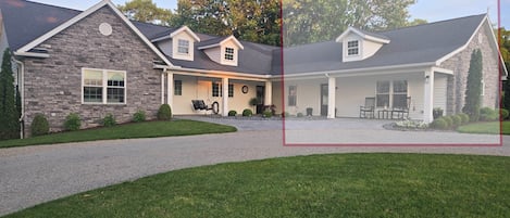 A two-story house with a stone facade, a covered porch, and a driveway.