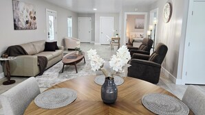 A spacious living room with a sofa, armchairs, a coffee table, and a dining table with placemats.