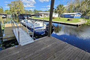 Ein Steg mit einem Boot, einer Holzpromenade und einem Gebäude im Hintergrund.