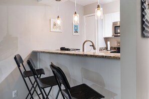 A kitchen with a granite countertop, stainless steel appliances, and pendant lighting.