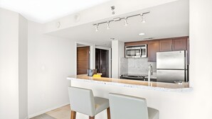 Uma cozinha moderna com ilha central, eletrodomésticos de aço inoxidável e banquetas de bar.