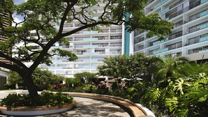 Um edifício moderno com várias varandas e um pátio ajardinado com árvores e plantas.