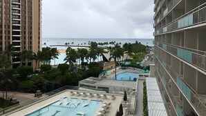Um hotel com área de piscina, vista para a praia e um edifício alto.