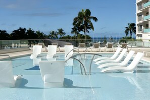 A pool area with lounge chairs and a view of the ocean. - Waikiki, Ilikai, Spacious 4 BR, Oceanfront, Sleeps 12 (Honolulu)