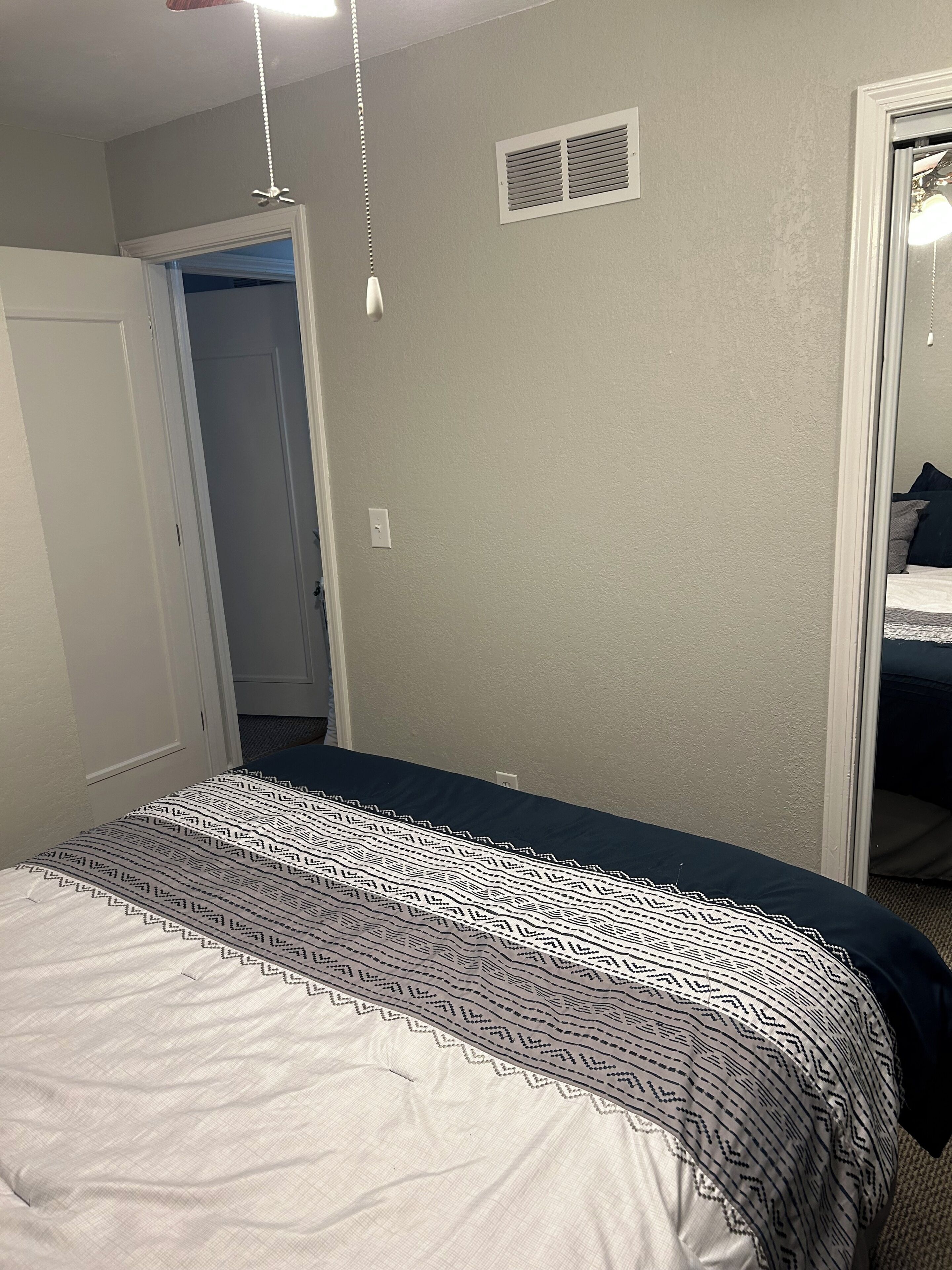 A bedroom with a bed, a closet, and a mirror.