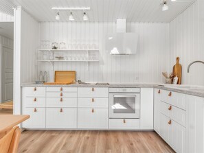 Una cocina moderna con armarios blancos, horno integrado y encimera de madera.
