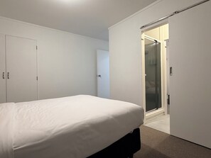 A bedroom with a bed, a wardrobe, and a shower area. - 3BR Home - Walk to Train, Lynn Mall & Westgate (Auckland)