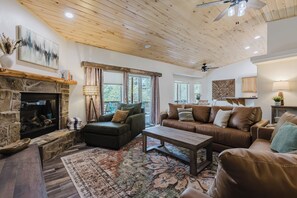 Ein gemütliches Wohnzimmer mit Kamin aus Stein, Ledersofas, einem Couchtisch und einem großen Teppich.