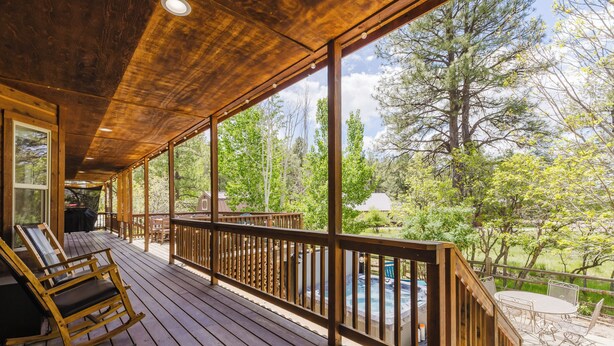 Terraza de madera con vista a una piscina y árboles.