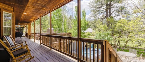 Terraza de madera con vista a una piscina y árboles.