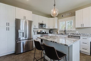 A modern kitchen with white cabinets, stainless steel appliances, a marble countertop, and a hanging light fixture. - 3BR Pet-Friendly Home | Fire Table, Fenced Yard + PLPOA Lake Access (Pagosa Springs)