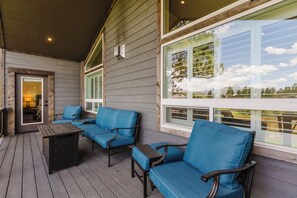 A covered outdoor seating area with a wooden deck, blue cushioned chairs, and a small table. - 3BR Pet-Friendly Home | Fire Table, Fenced Yard + PLPOA Lake Access (Pagosa Springs)