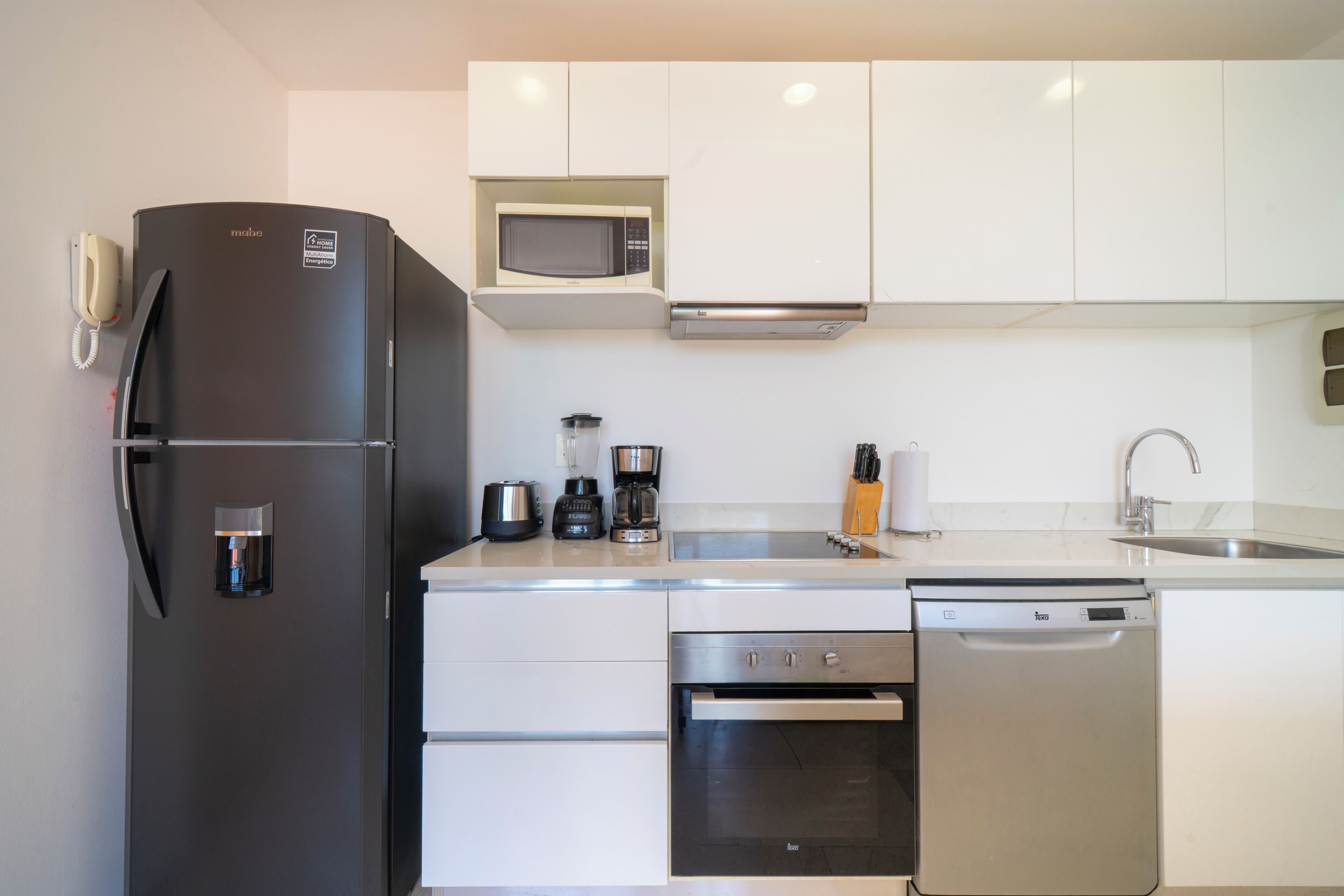 A modern kitchen with a refrigerator, microwave, coffee maker, and dishwasher.