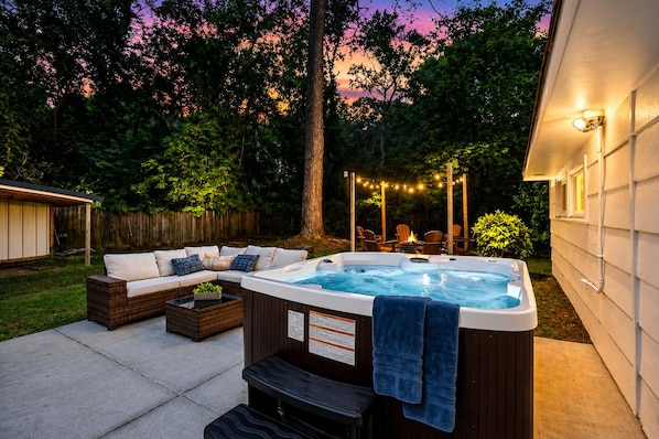 Ein Garten mit Whirlpool, Gartenmöbeln und Lichterketten.