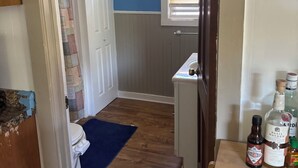 Une salle de bain comprenant des toilettes, une douche, un lavabo et une fenêtre avec des stores.