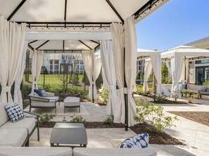Un espace extérieur abrité, aménagé avec une table de patio, des chaises et un canapé.